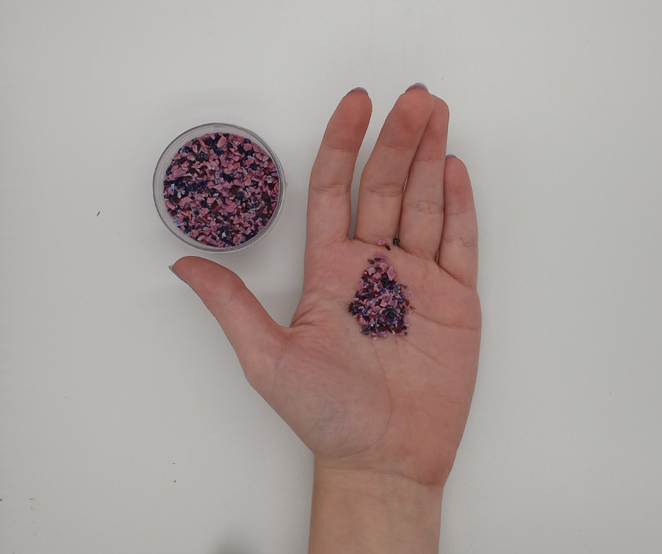 hand holding loose frit and an open jar