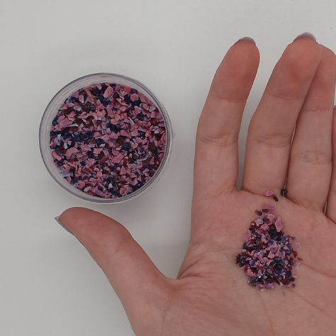 hand holding loose frit and an open jar