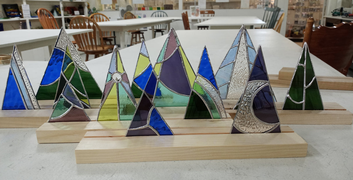 Colorful glass mountain sculptures on wooden stands in a workshop setting