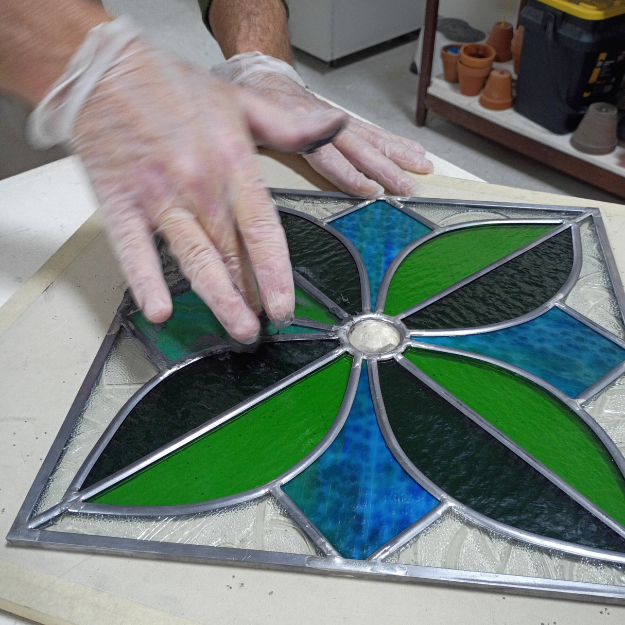 person wearing gloves applying putty to lead came panel