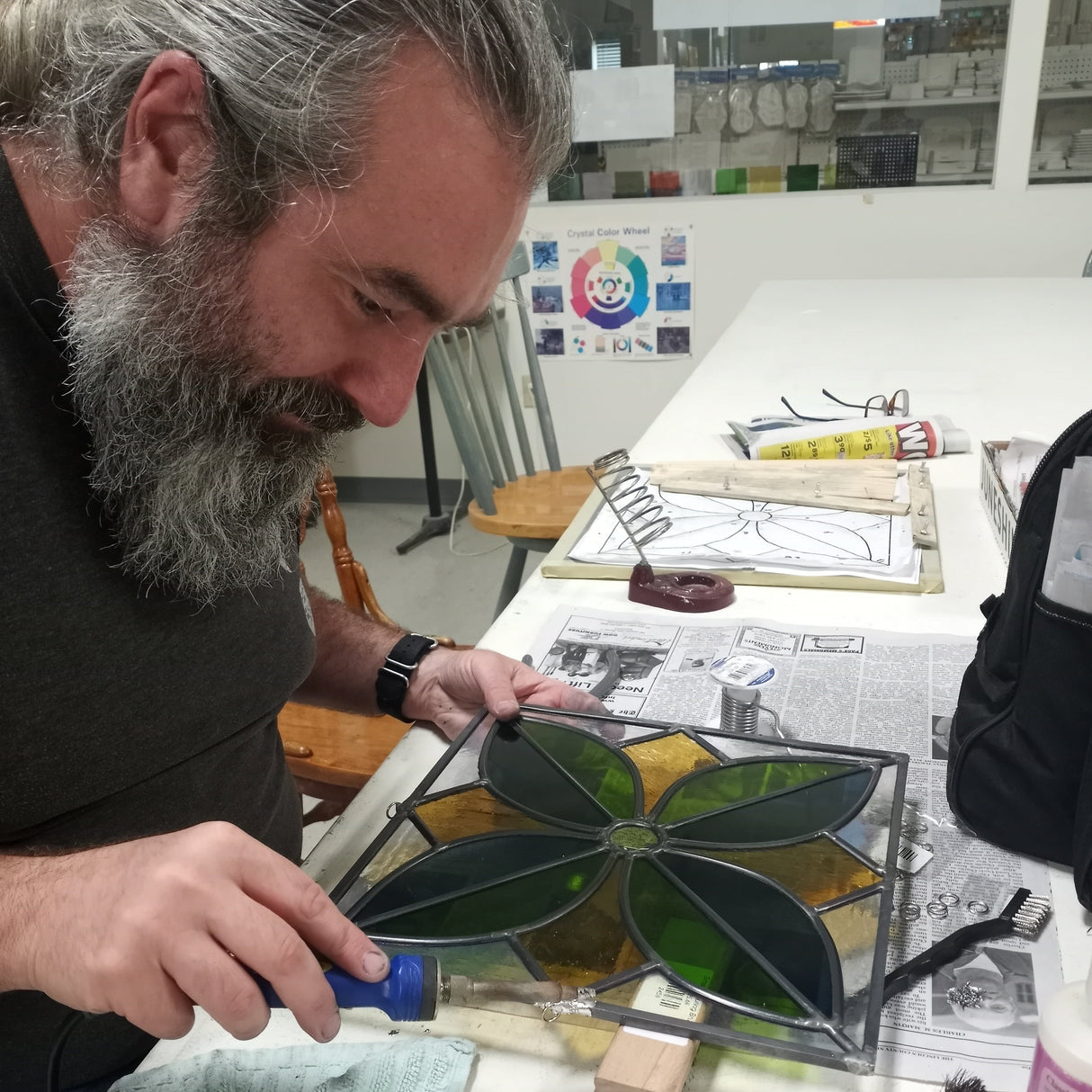 Man working on a stained glass project in a workshop.