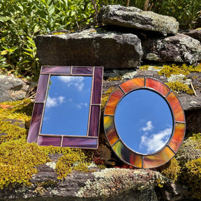 Two decorative mirrors on a stone surface with a natural background