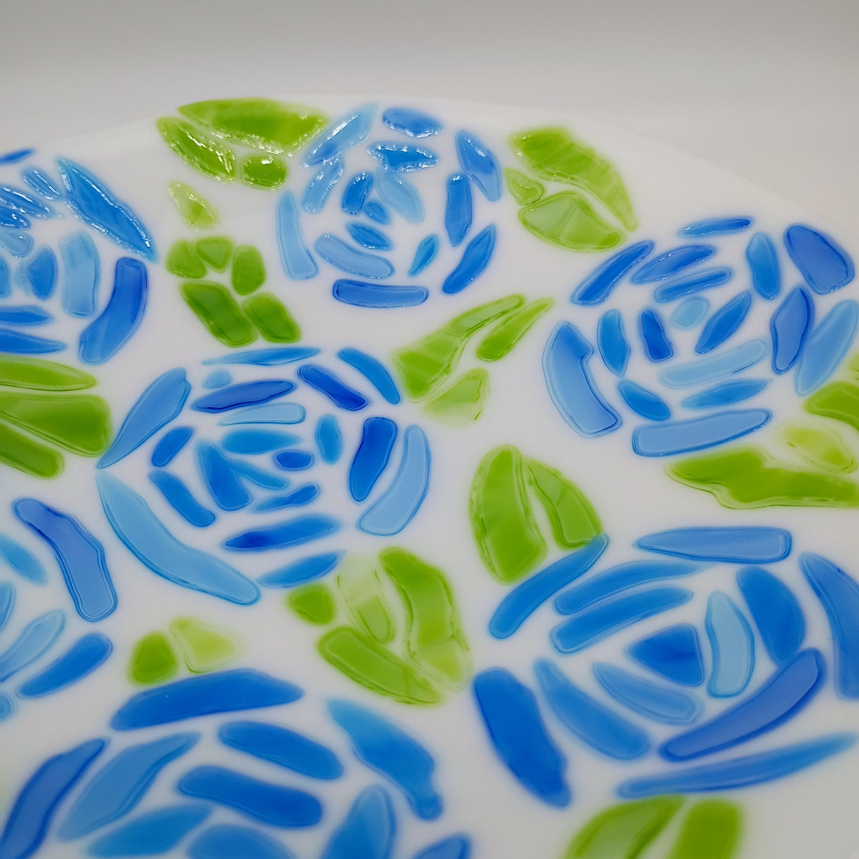 Decorative plate with blue and green floral pattern on a white background