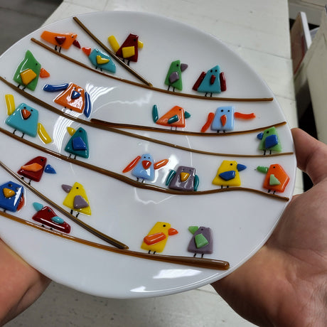 white fused glass plate with multicolored birds closeup