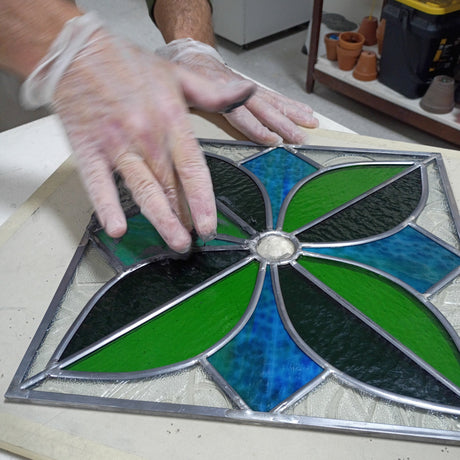 person wearing gloves applying putty to lead came panel